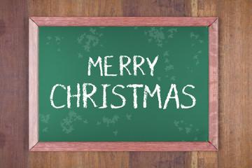 Chalkboard with christmas decoration on a wooden background and text 