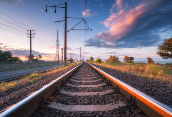 Railroad and beautiful sky at sunset in summer. Rural industrial landscape with railway station,...