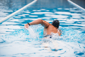 Athletic Young man swimming the back crawl in a pool. Swimming competition.
