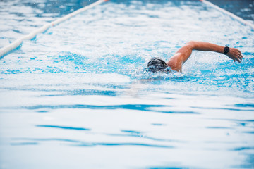 Athletic Young man swimming the front crawl in a pool. Swimming competition.