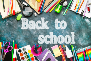 Back to school background with text chalk imitation, notebooks, pens, pencils, other stationery on blue chalk board desk, education concept, flat lay, top view