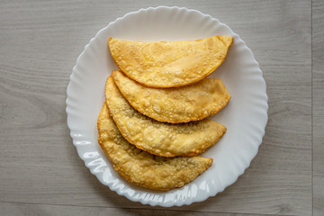 A bunch of four Brazilian fried pastes over a white plate on a wooden table