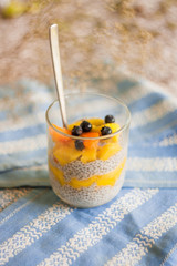  mango and chia seed pudding in a glass tumbler stands on a blue napkin
