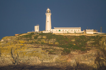 Lighthouse on rocky outcrop in morning light, landscape