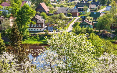 Village with blooming gardens of cherry trees and bird cherry on  banks of  river