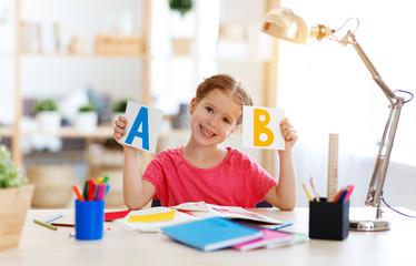 funny child  girl  doing homework writing and reading at home.