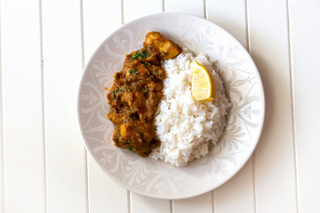 Close up traditional Indian butter chicken curry and lemon served with chapati bread on banana leaf.