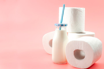 Lactose intolerance and the inability to digest milk concept theme with a bottle of milk with a blue straw and roll of toilet paper isolated on pink background with copy space
