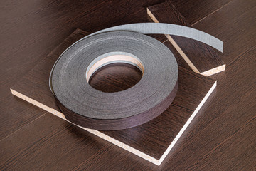 Roll melamine edge for finishing of furniture. Edging tape lying on laminated chipboard sheets...