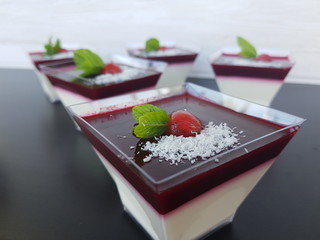 Panna cotta in a transparent glass with strawberry filling, chocolate and mint.