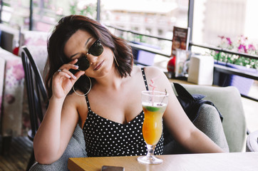 candid woman in polka dot dress drinking cocktail in cafe