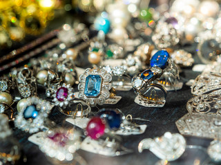 Defocused view of jewelry store with multiple rings and earrings with blue magenta precious and semiprecious stones for sale as seen in Spanish showcase fashion store