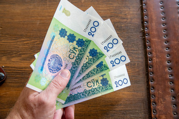 Hand holding Uzbekistani money, known as So'm
