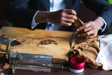Process of making traditional cigars from tobacco leaves with hands using a mechanical device and...