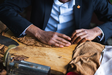 Process of making traditional cigars from tobacco leaves with hands using a mechanical device and press. 
