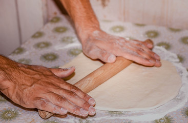 men's hands kneading dough on the table
