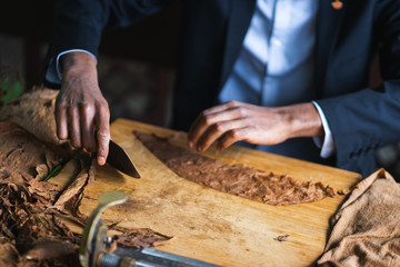 Process of making traditional cigars from tobacco leaves with hands using a mechanical device and press. 