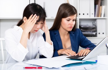 Women reading documents with upset faces at office