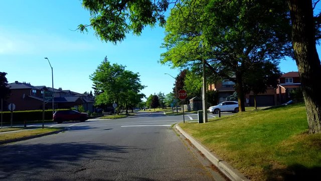 Viewpoint of City Suburb Four-Way Stop Sign Intersection Road With Traffic in Day.  Vehicles Stop and Go at All-Way Stop Intersection Street.