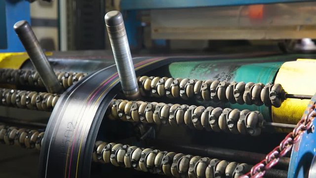 Manufacture of tires. Machine for marking rubber bands with colored paints cutting into pieces for the further production of automobile tires. Cutting rubber bands into pieces at a tire factory.