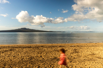 Young kid playing in the beach in front of a beautiful mountain