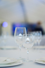 Clean empty glasses and plates on the table in the restaurant prepared for guests. 