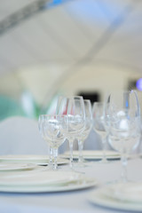 Clean empty glasses and plates on the table in the restaurant prepared for guests. 