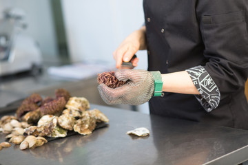 Master class. Chef cuts sea urchin in the kitchen of a restaurant. Closeup of a hand with a knife...