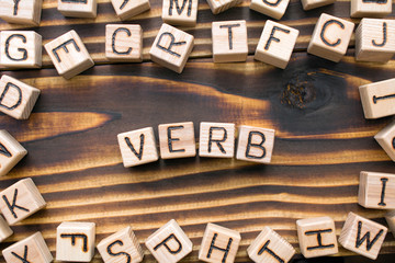 word verb composed of wooden cubes with letters, Part of speech concept scattered around the cubes random letters, top view on wooden background