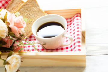 Fresh morning coffee with bread, rose in tray on the bed, early work day. Lifestyle Concept