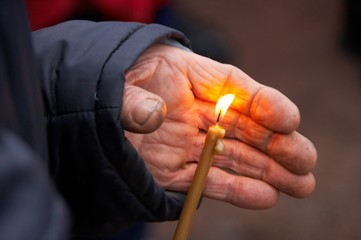 Single flaming candle in old female hands