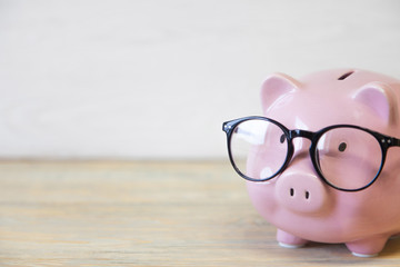 Piggy bank with glasses on the wooden background