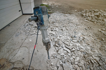 Removing concrete floor with jackhammer tool. Concrete rubble debris on construction site....