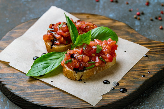 bruschetta with tomatoes and basyl on board on blue concrete table