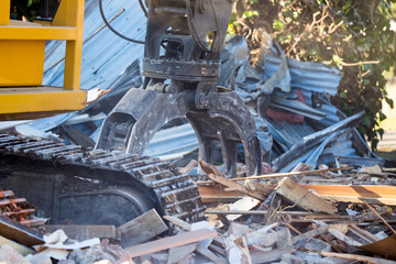 A large powerful digger is used at a demolition site to crush and remove and old building in New...