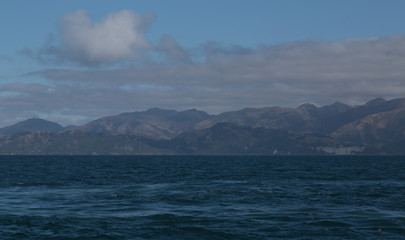 Delightful sea landscape with blue surface of the water, magic feather clouds on the sky over mountain in Kaikoura,New Zealand
