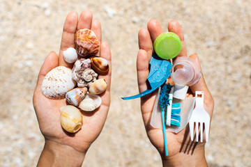 Concept of choice: save nature or continue to use disposable plastic. One hand holding beautiful shells, in the other - plastic waste. Beach sand on background. Environmental pollution problem. - 280117452
