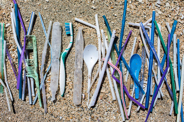 Heap of different plastic waste: straws and single-use spoons, toothbrush and comb collected on the...