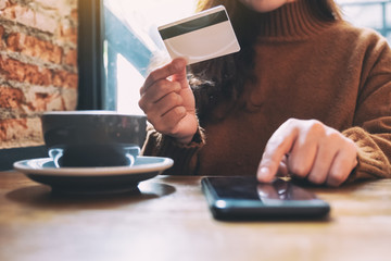 A woman holding credit card and pointing at mobile phone for purchasing and shopping online