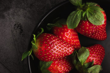 Fresh red strawberries in bowl. Strawberry fruits on dark stone table copy space for text. top view.