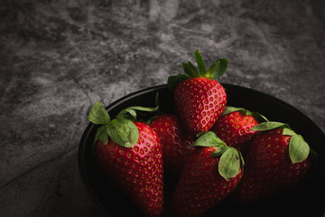 Fresh red strawberries in bowl. Strawberry fruits on dark stone table copy space for text. top view.