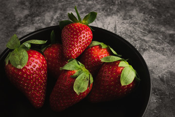 Fresh red strawberries in bowl. Strawberry fruits on dark stone table copy space for text. top view.