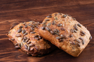 Roll breads with pumpkin seeds on a wooden background.
