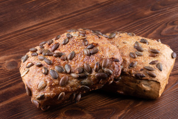 Roll breads with pumpkin seeds on a wooden background.