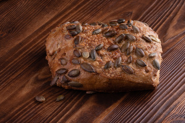 Roll breads with pumpkin seeds on a wooden background.