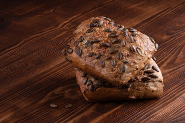 Roll breads with pumpkin seeds on a wooden background.