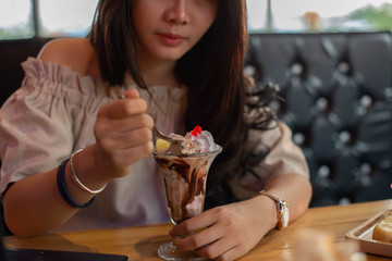 Beautiful girl sitting to eat ice cream in a restaurant