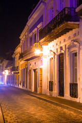 Fototapeta na wymiar Empty street scene from Old San Juan Puerto Rico at night with buildings and cobblestones. 
