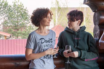 Two girlfriends drinking wine and chatting on a rustic background