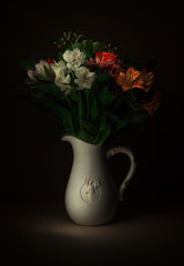Summer floral composition in a jug on black background